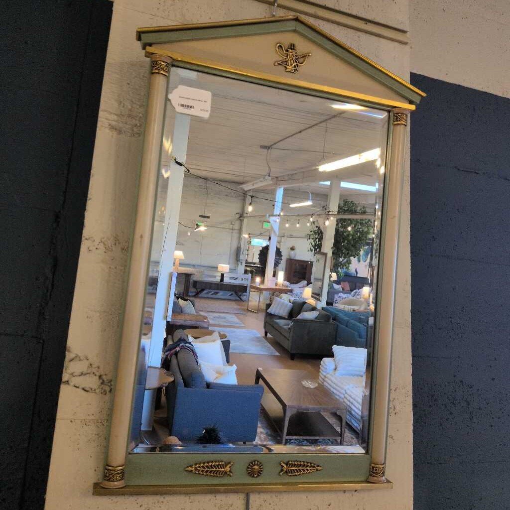 Decorative mirror with gold accents reflecting a room with furniture.