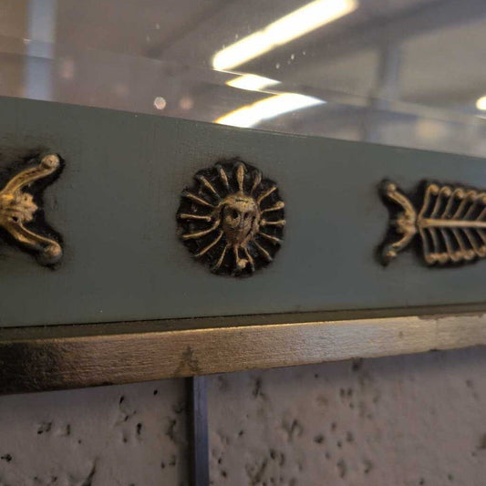 Decorative metal strip with embossed designs on a reflective surface
