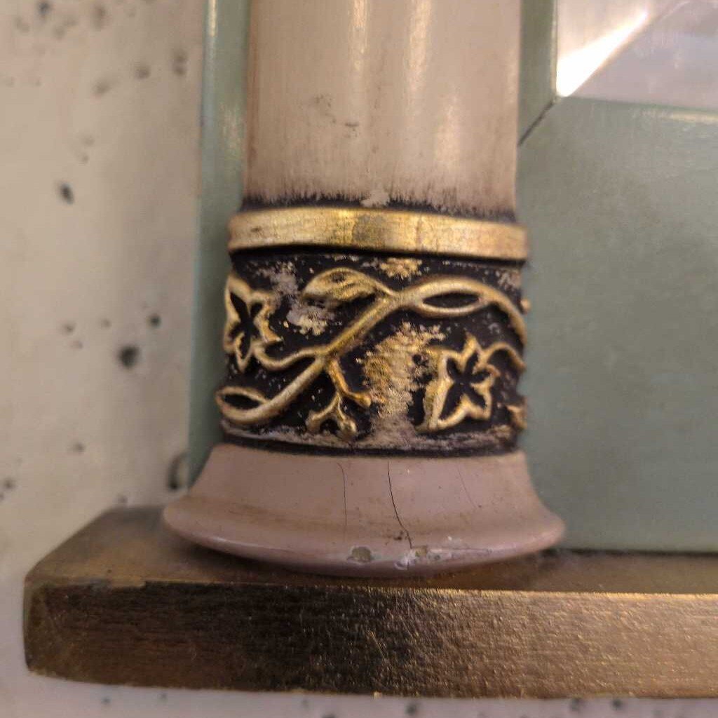 Decorative candle holder with gold and black design on a wooden surface.