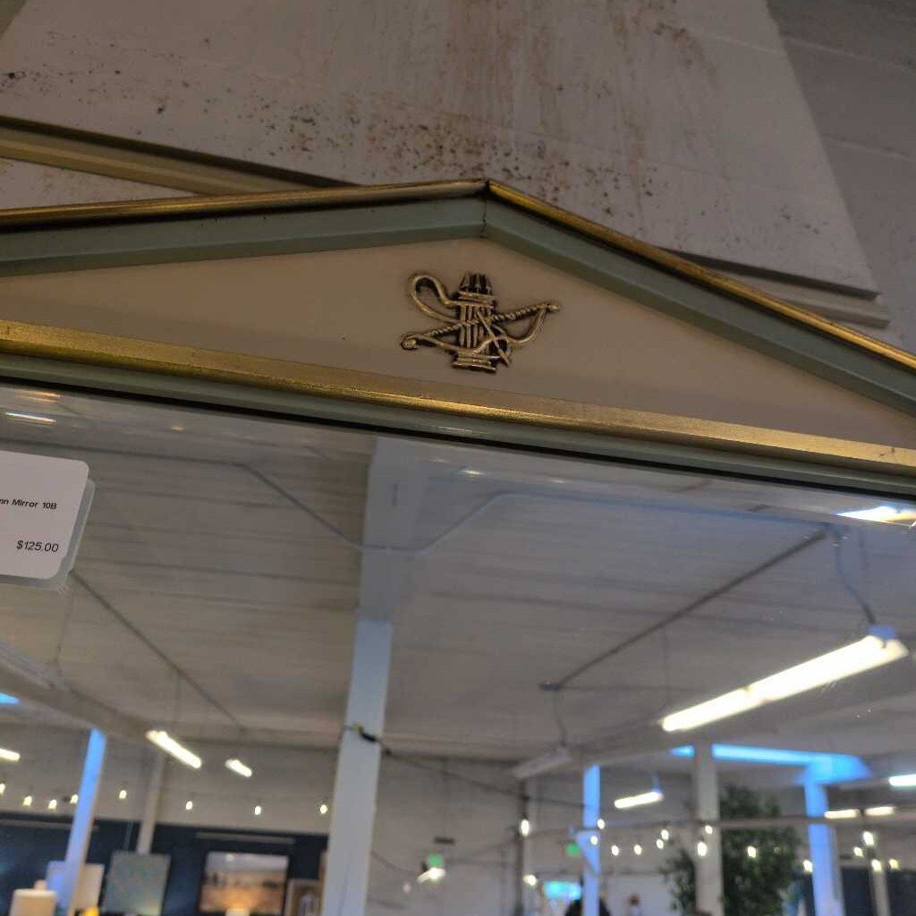 Decorative mirror with gold frame and emblem in a store setting