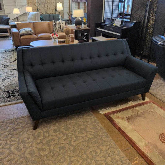 Dark gray sofa in a living room setting with a piano and decorative items.