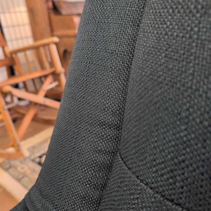 Close-up of dark gray fabric texture with wooden chairs in the background