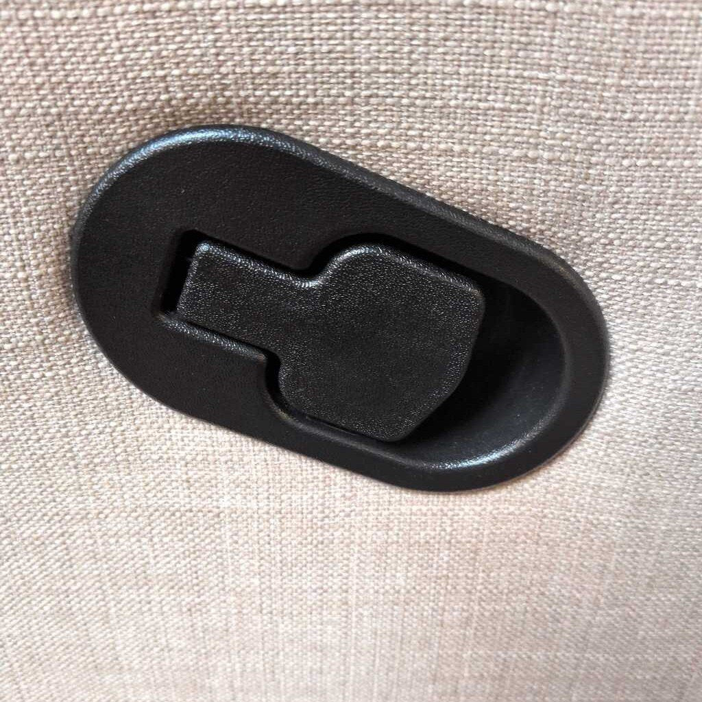 Black plastic latch on a beige fabric background
