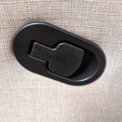 Black plastic latch on a beige fabric background
