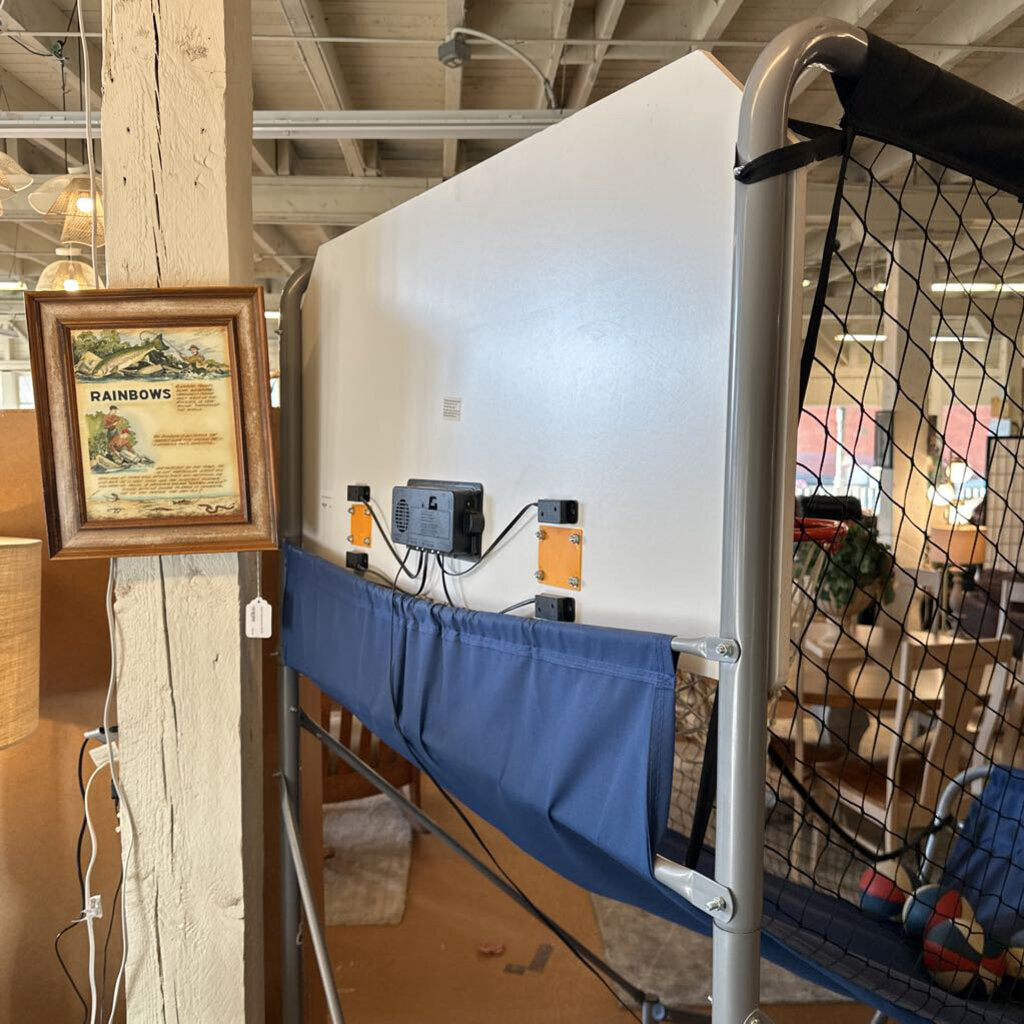 Indoor setting with a large white screen, blue chair, and framed picture on a wooden post.