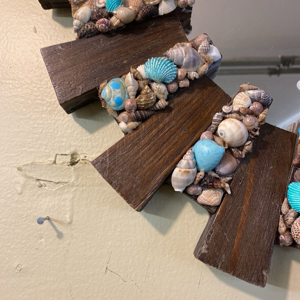 Decorative wall art with seashells and wooden blocks on a textured surface