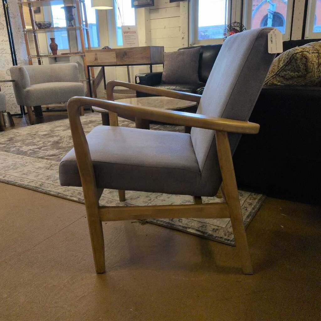 Gray armchair with wooden arms in a room with furniture and decor.