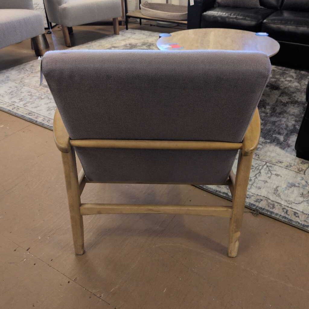 Chair with gray cushioned backrest and wooden frame on a brown floor.