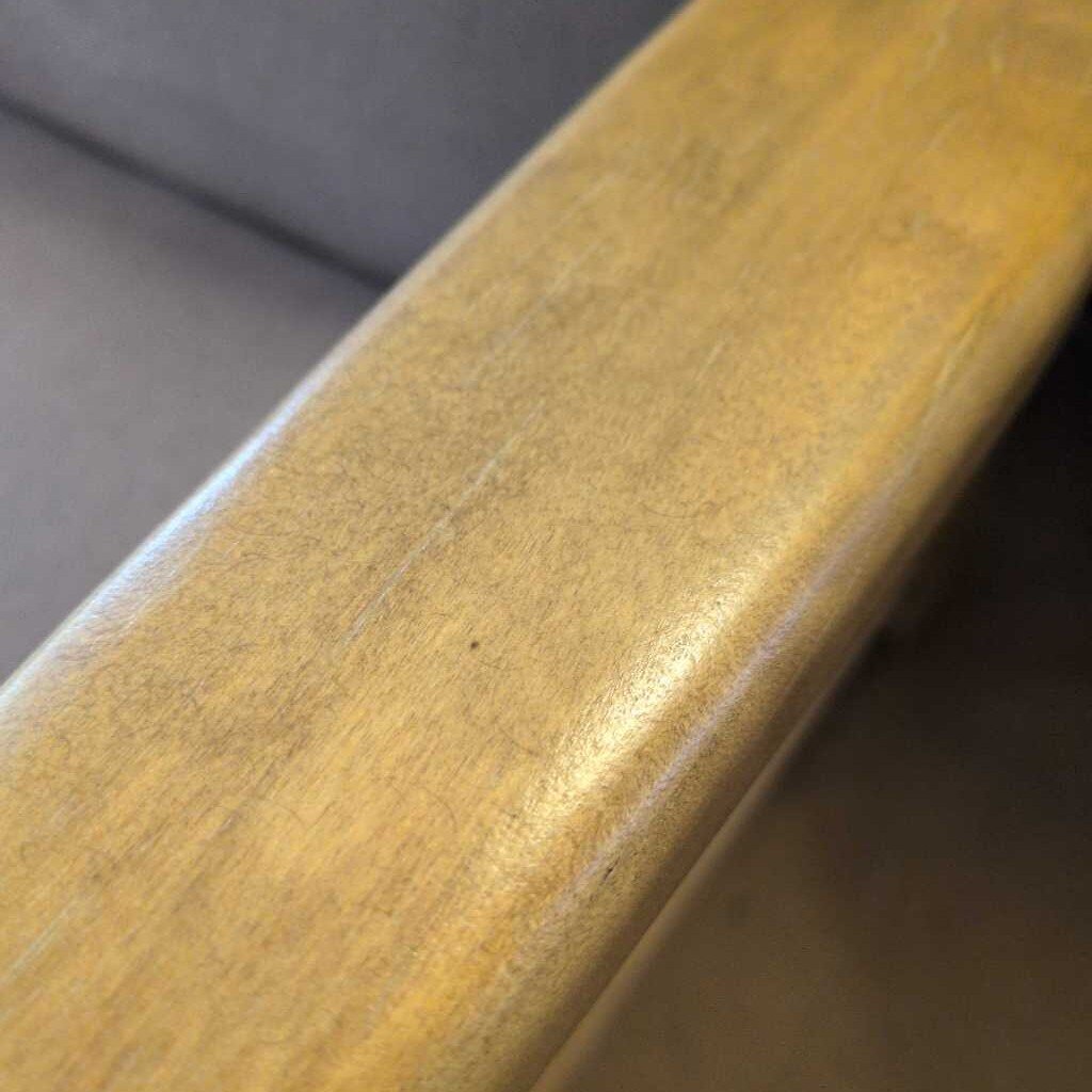 Close-up of a wooden chair armrest with a blurred background