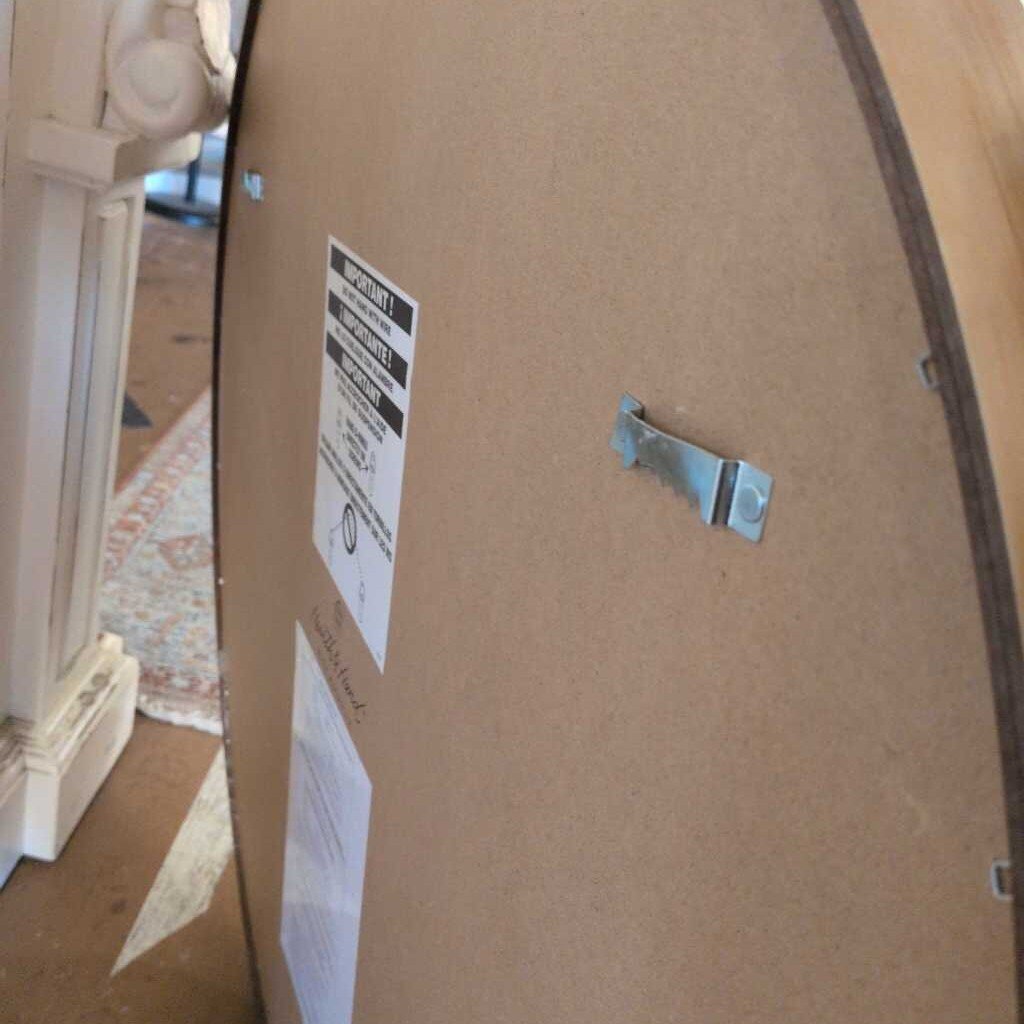 Cardboard box with labels and tape, partially open, on a wooden floor.