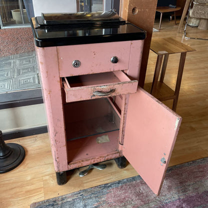 Pink metal cabinet with open door on a wooden floor