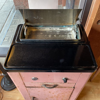 Vintage metal appliance with open lid on a wooden cabinet