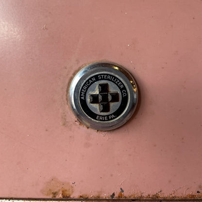 Metallic button with 'American Sterilizer Co' branding on a pink background