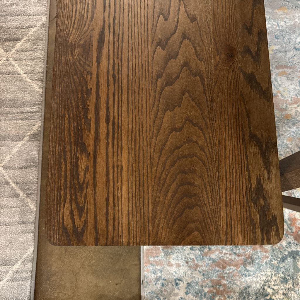 Wooden surface with a visible grain pattern on a textured floor.