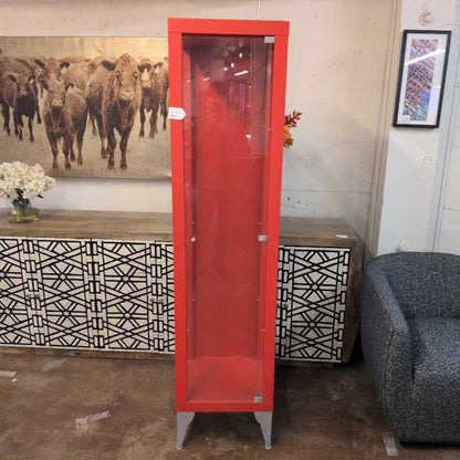 Red glass-fronted cabinet in a room with decorative elements and furniture.