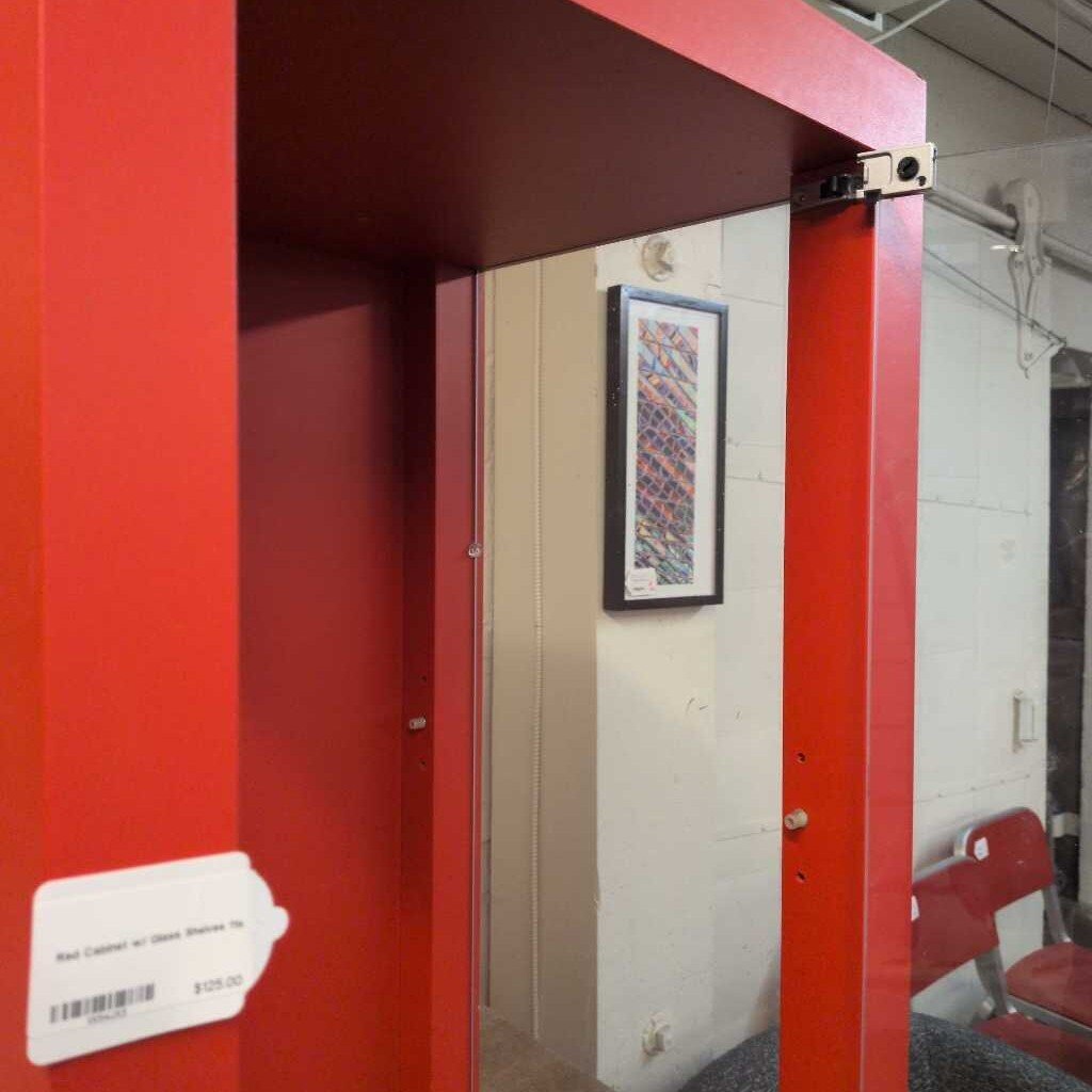 Red booth with a door and a framed picture on a wall inside a building.