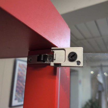 Metal hinge on a red surface with a blurred indoor background