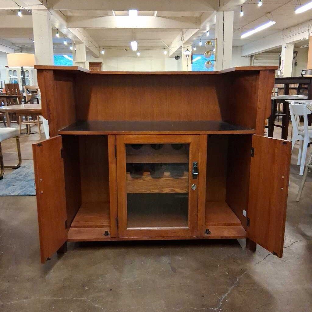 Wooden bar cabinet with open doors in a showroom setting