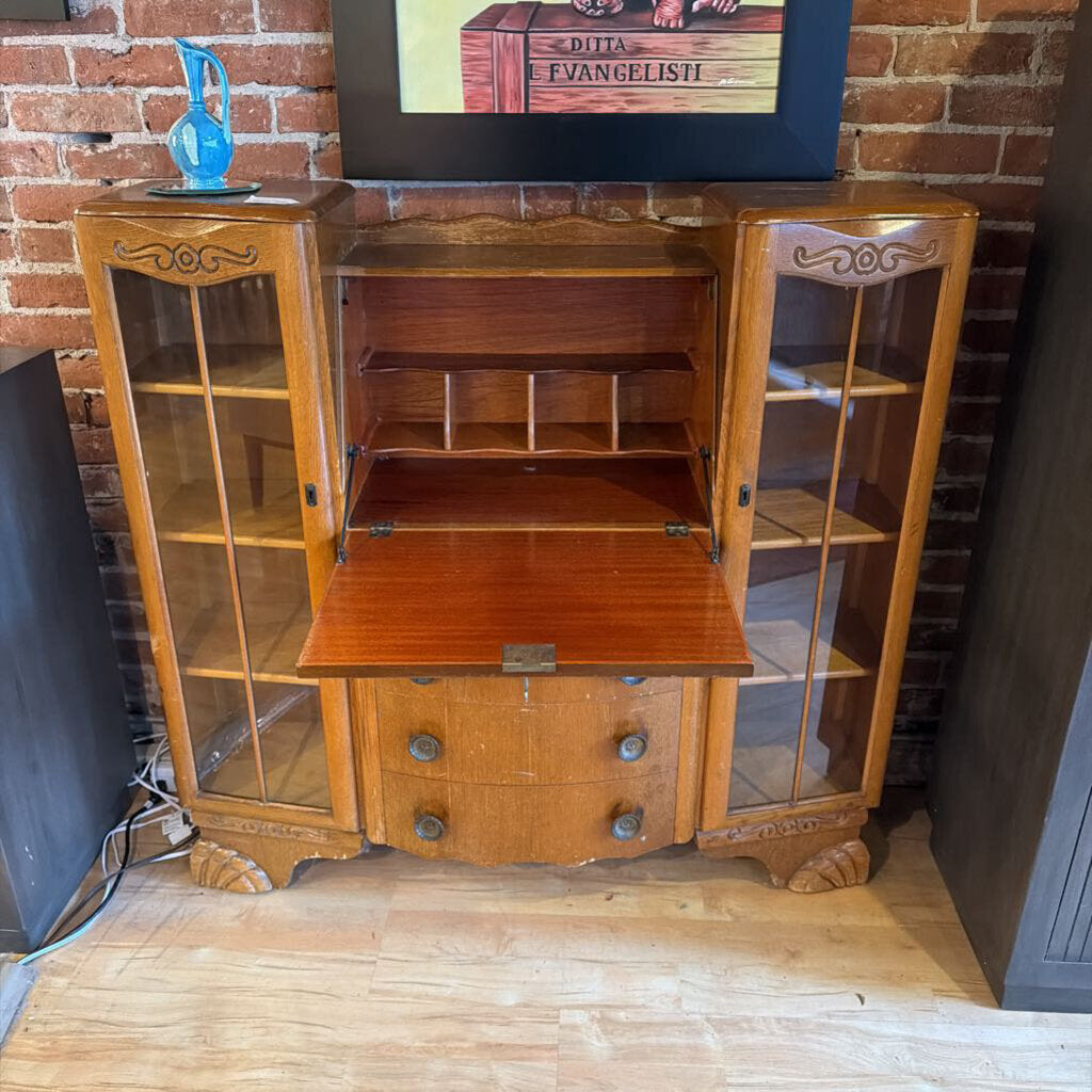 Wooden cabinet with glass doors against a brick wall