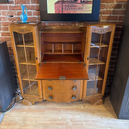 Wooden cabinet with glass doors against a brick wall