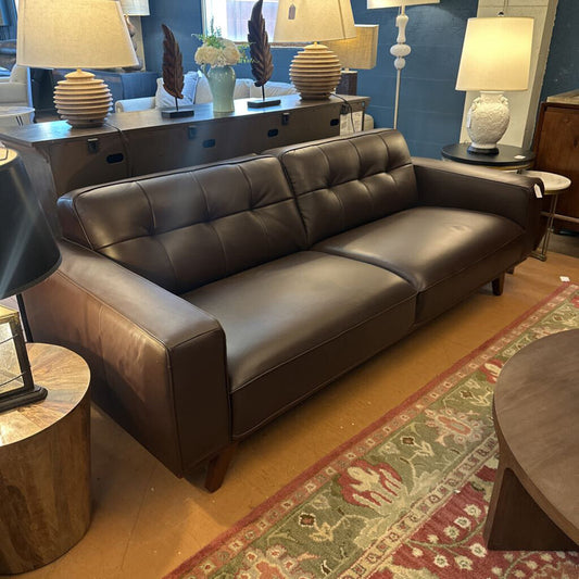 Brown leather sofa in a living room setting with decor elements.