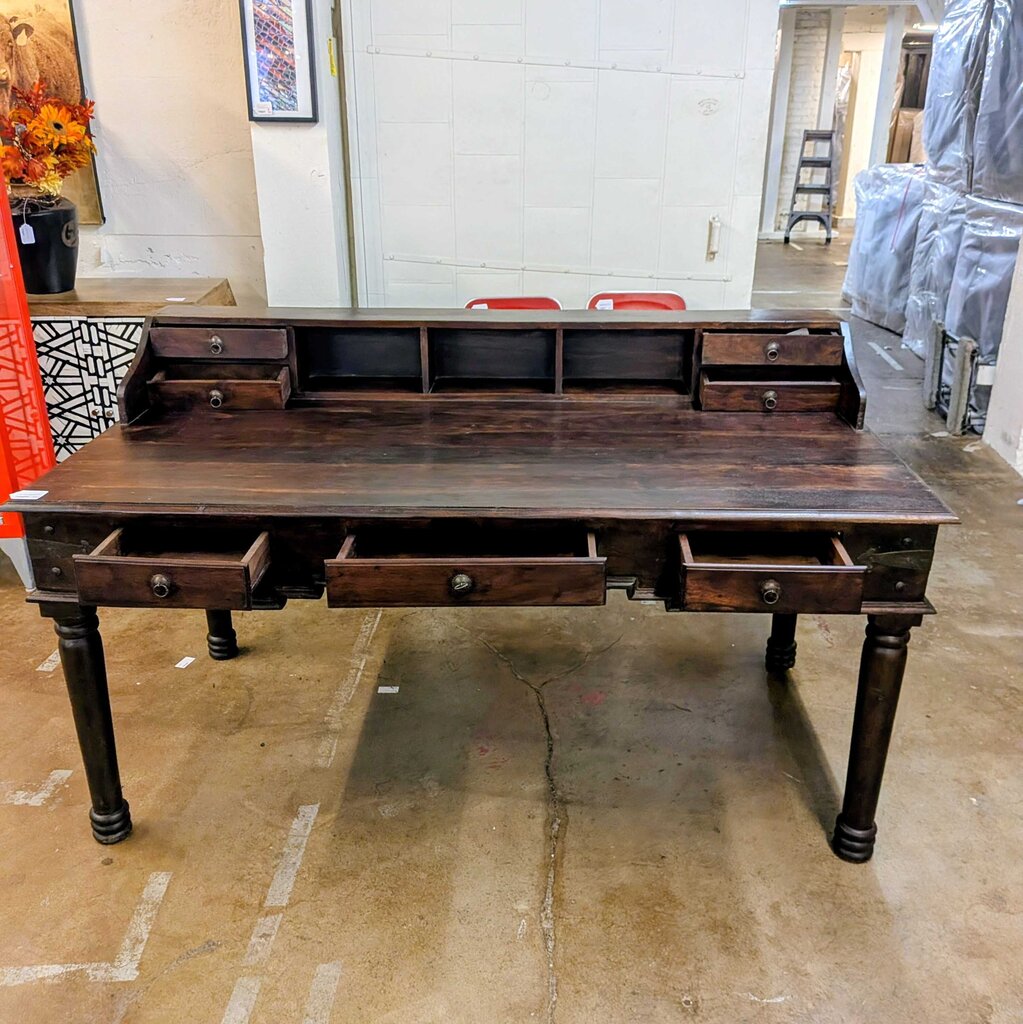 Large wooden desk with multiple drawers in a warehouse setting
