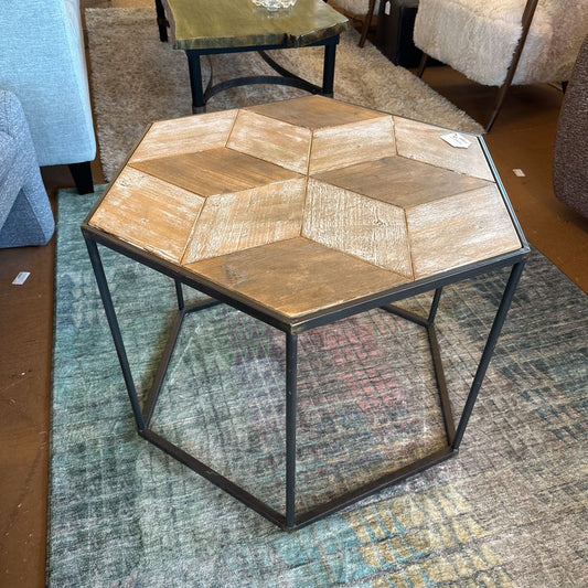 Hexagonal wooden table with metal legs on a textured rug