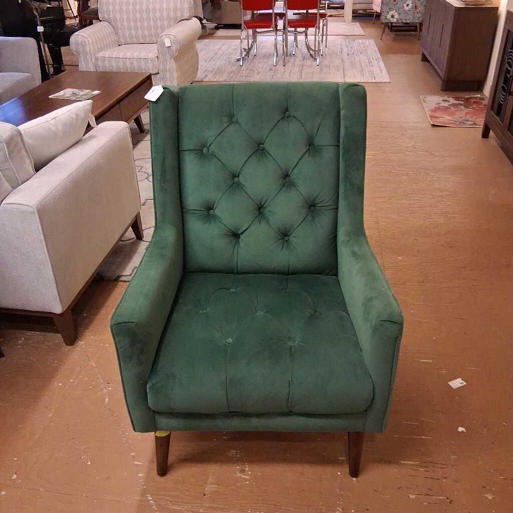 Green upholstered armchair in a room with furniture and flooring.