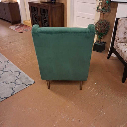Green armchair in a room with wooden floor and furniture.