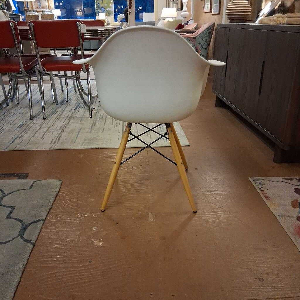 White chair with wooden legs on a wooden floor in a furniture store