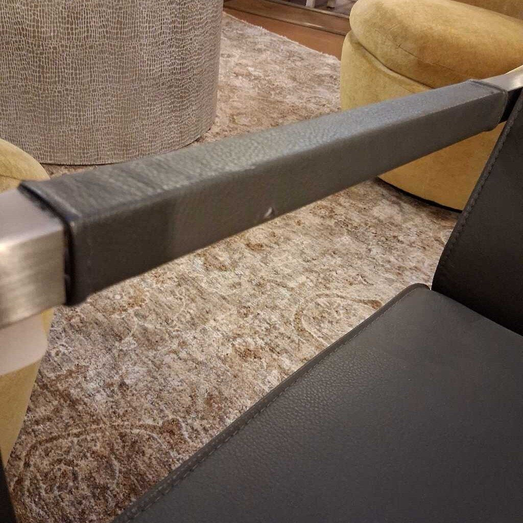 Close-up of a metal chair armrest with a blurred indoor background