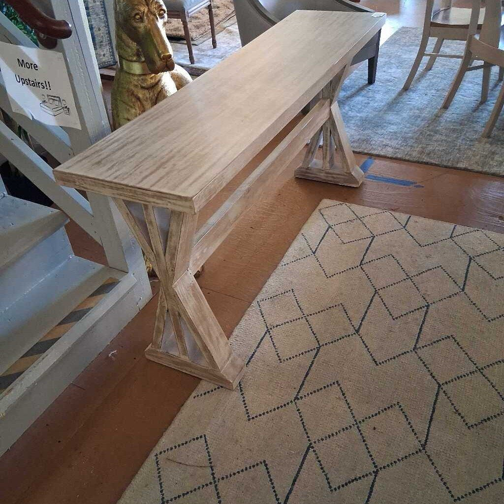 Wooden console table in a room with a patterned rug and furniture.