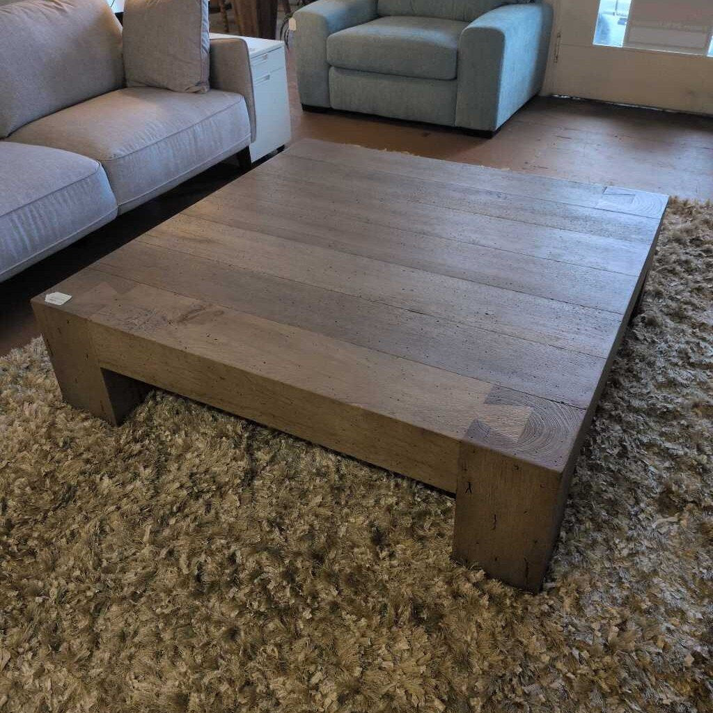 Wooden coffee table in a living room with beige sofa and armchair.