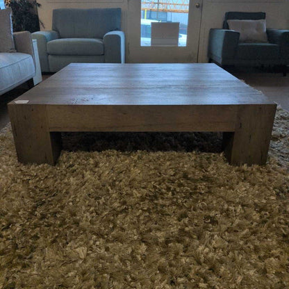 Wooden coffee table in a living room setting with furniture and a rug.