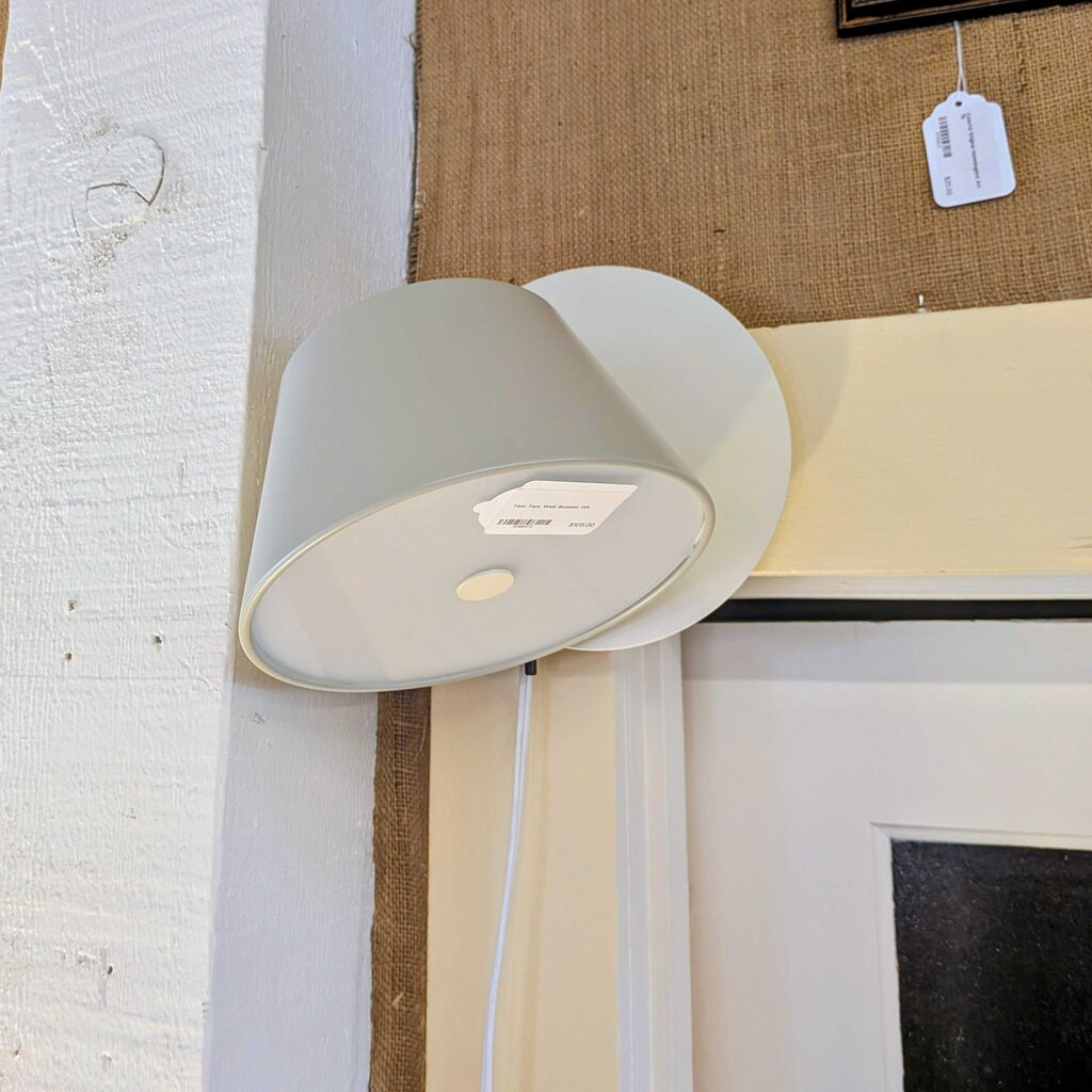 Wall-mounted lamp with a white shade against a textured wall.