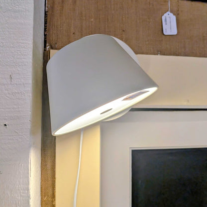 White lampshade on a wall next to a framed picture