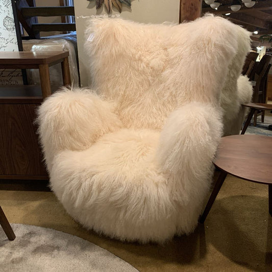 Fluffy white chair in a room with wooden furniture and decor.