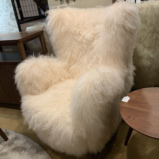 Fluffy white chair in a room with wooden furniture and decor.