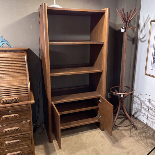 Wooden bookshelf with open door in a room setting with other furniture.
