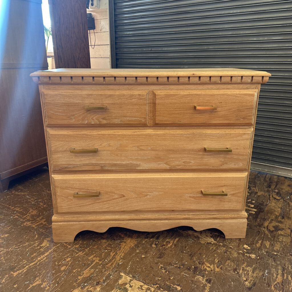 Wooden dresser with four drawers on a worn floor.