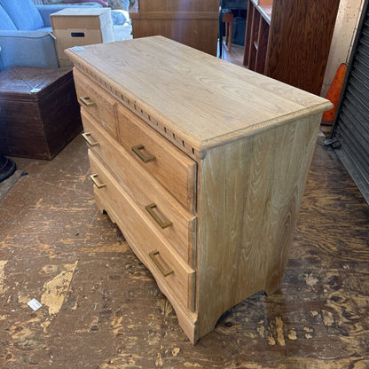 Wooden dresser with multiple drawers on a wooden floor.