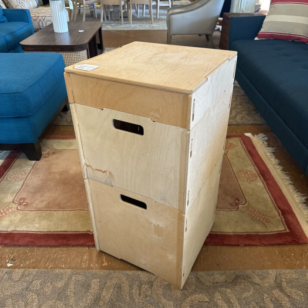 Wooden storage box on a patterned rug with furniture in the background