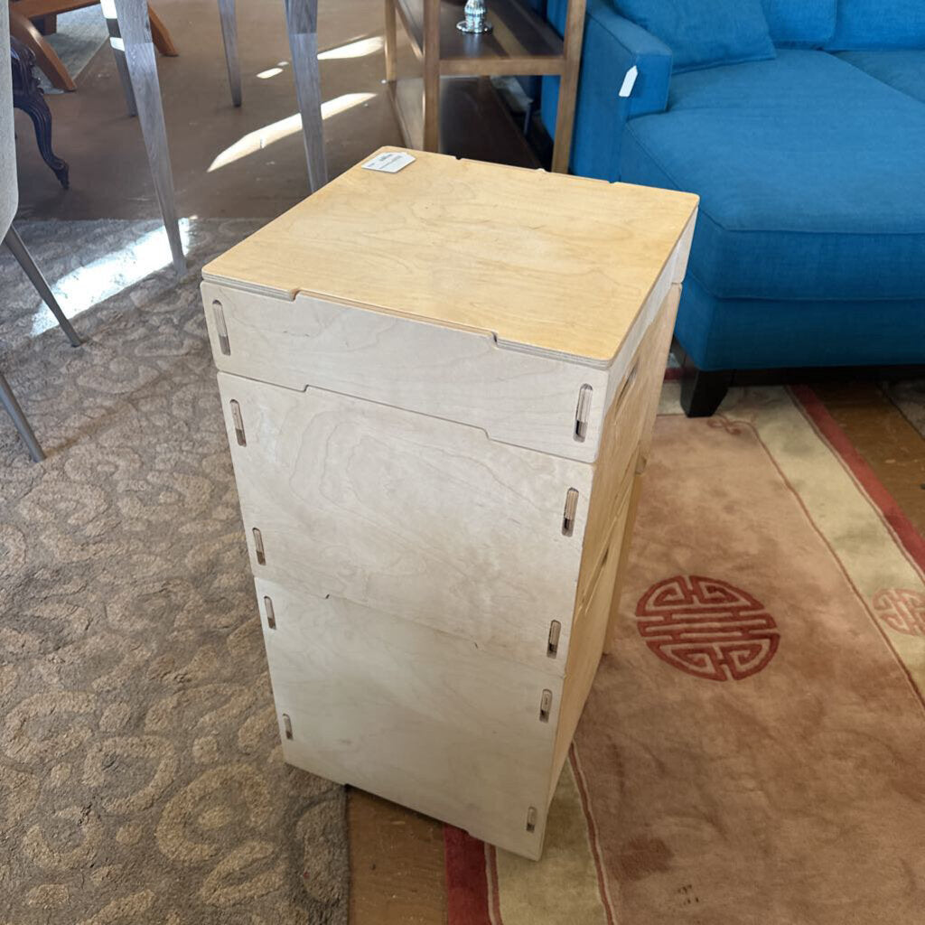 Wooden storage unit in a living room with a blue couch and patterned rug.