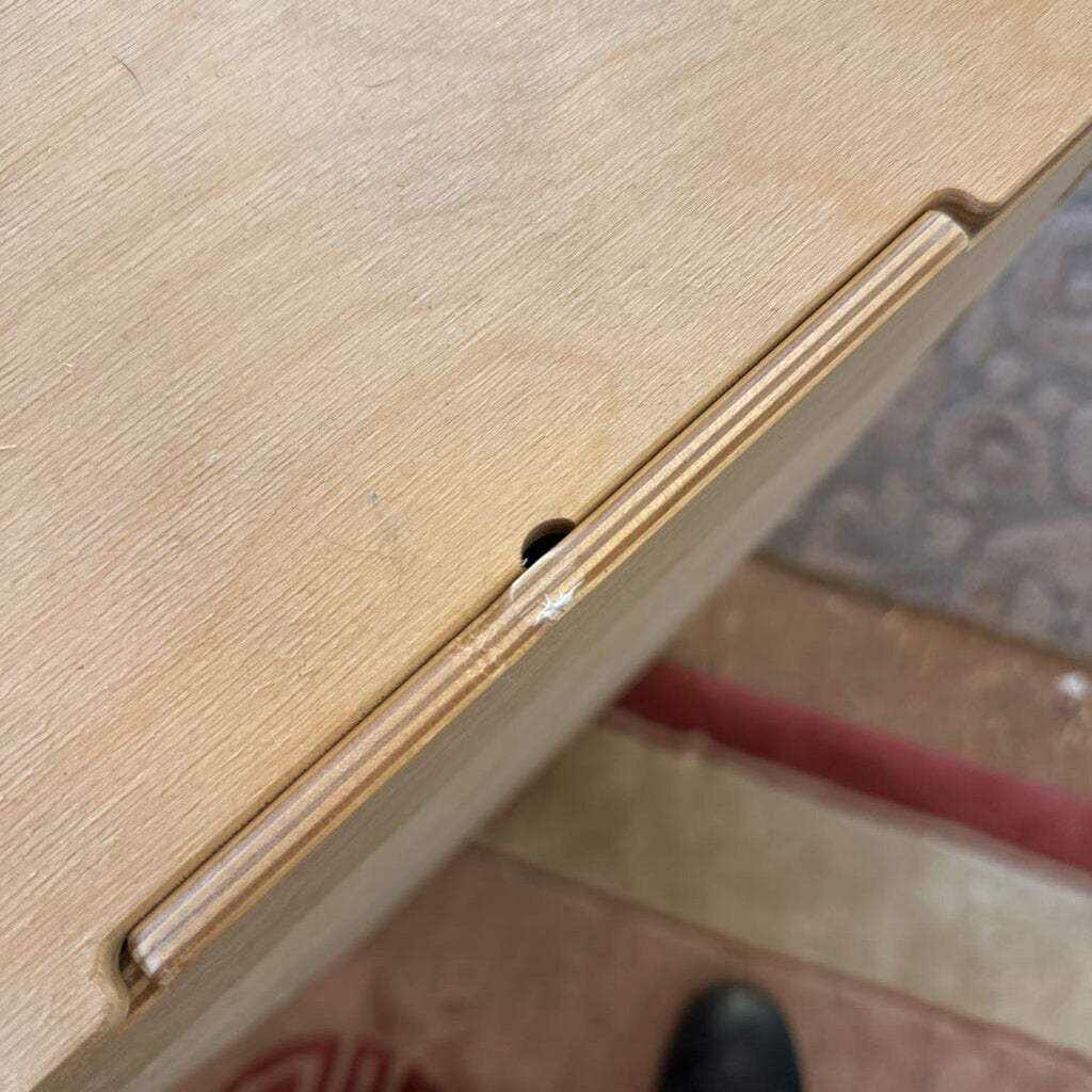 Close-up of a wooden surface with a small black object on it.