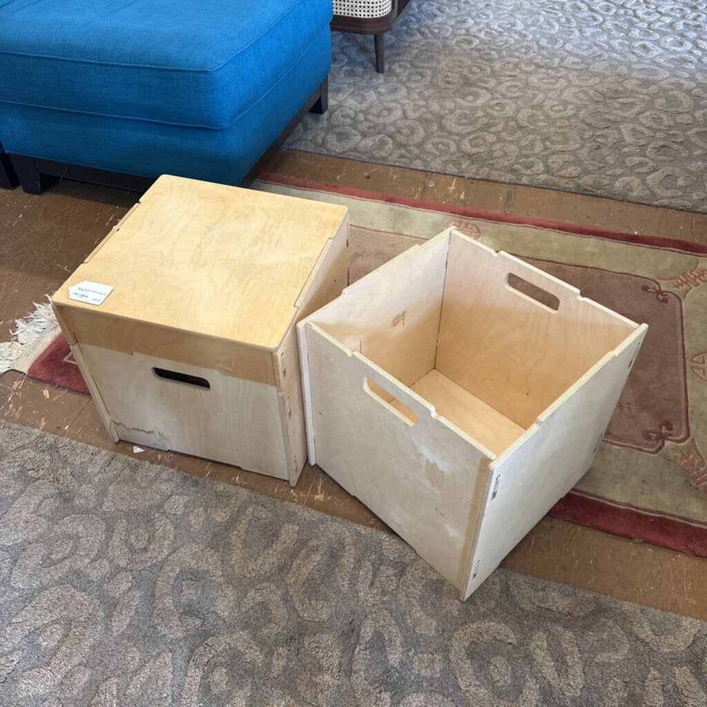 Two wooden storage boxes on a patterned carpet with a blue ottoman in the background.
