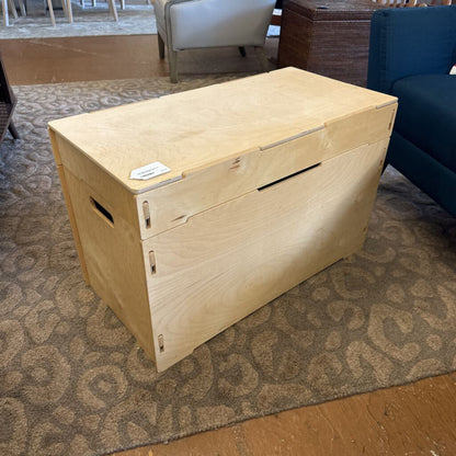 Wooden storage box on a patterned carpet with furniture in the background