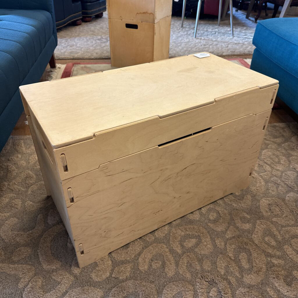 Wooden storage box on a carpeted floor with furniture in the background