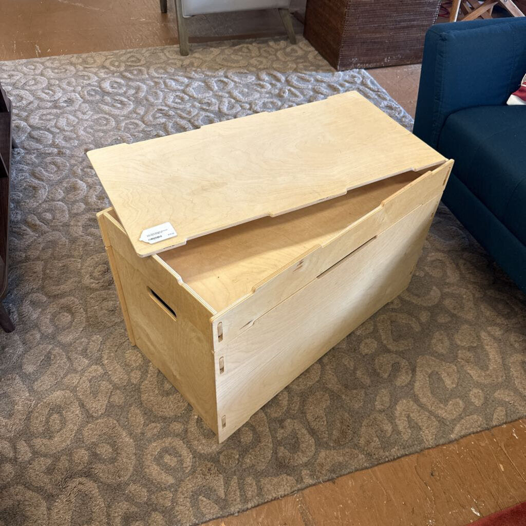Wooden storage box on a patterned carpet with a blue chair in the background