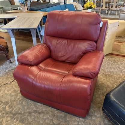 Red leather armchair in a showroom setting with other furniture.