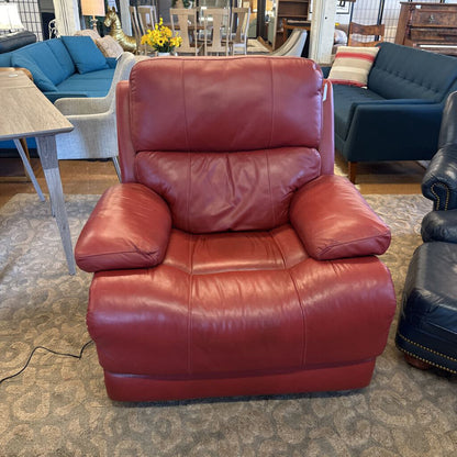 Red leather recliner chair in a furniture store setting with other chairs and tables.